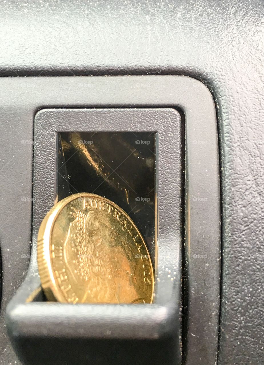 Australian one dollar coin in car dash coin slot closeup car interior