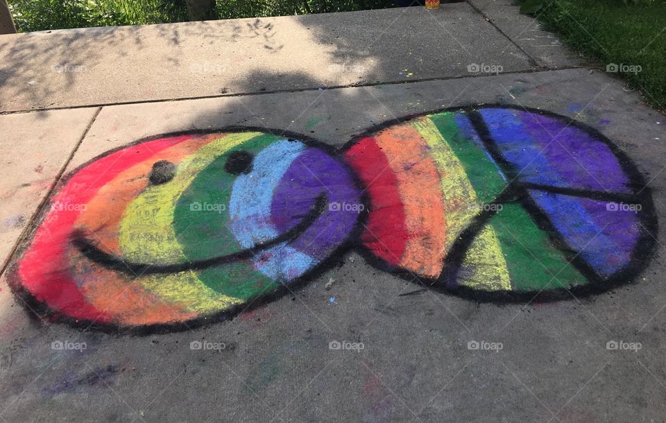 Rainbow smiley face and peace sign sidewalk chalk at. LGBT Pride. 