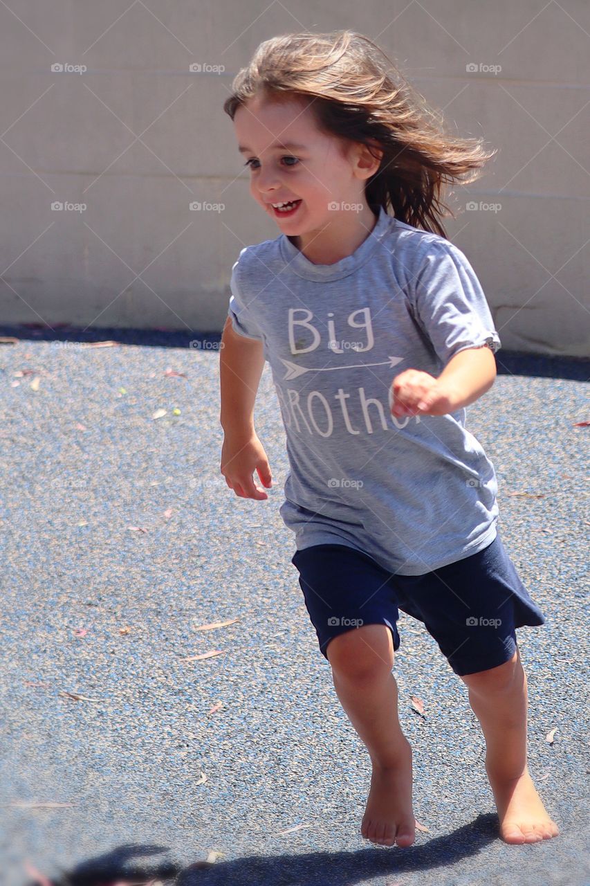 A happy young child runs at a playground on a sunny day. Ocean Beach, California 