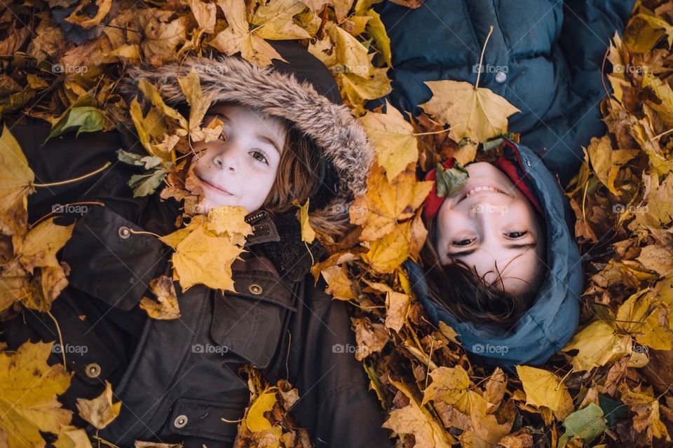 Boys laying down in the fall leaves