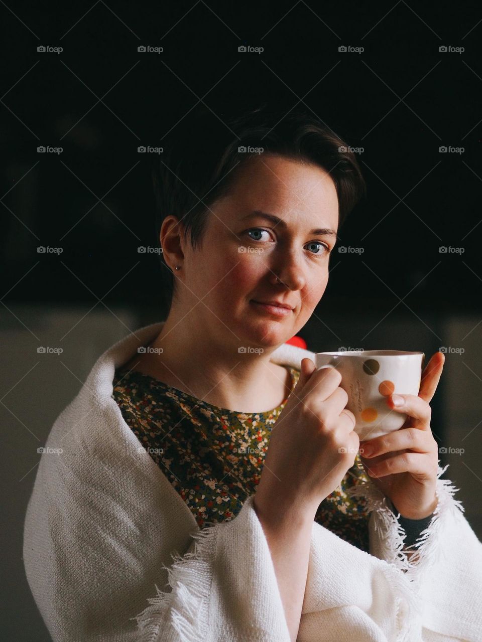 Portrait of young beautiful woman with cup, looking at camera