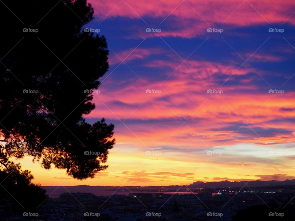 View of colorful sky at sunset overlooking the old town and sea in Nice, France.
