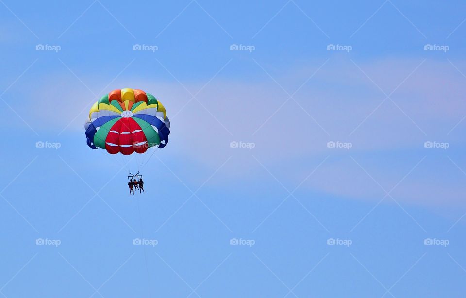 Low angle view of people parasailing against blue sky