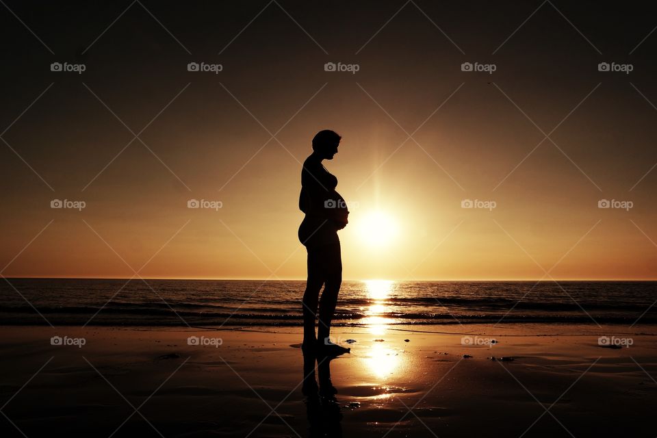 Young pregnant woman, on the beach in Holland. During sunset