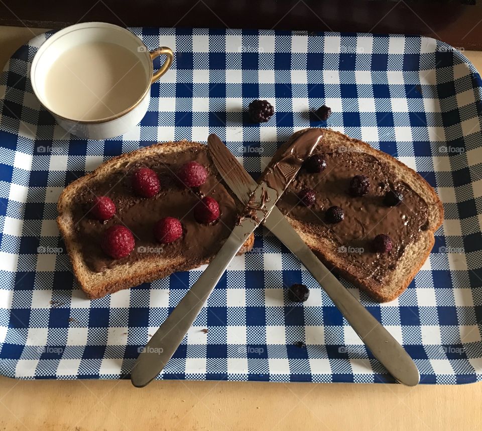 A yummy and delicious chocolate Nutella sandwich with Raspberries and BlackBerries two butter knives crisscrossing on the sandwich halves. USA, America 
