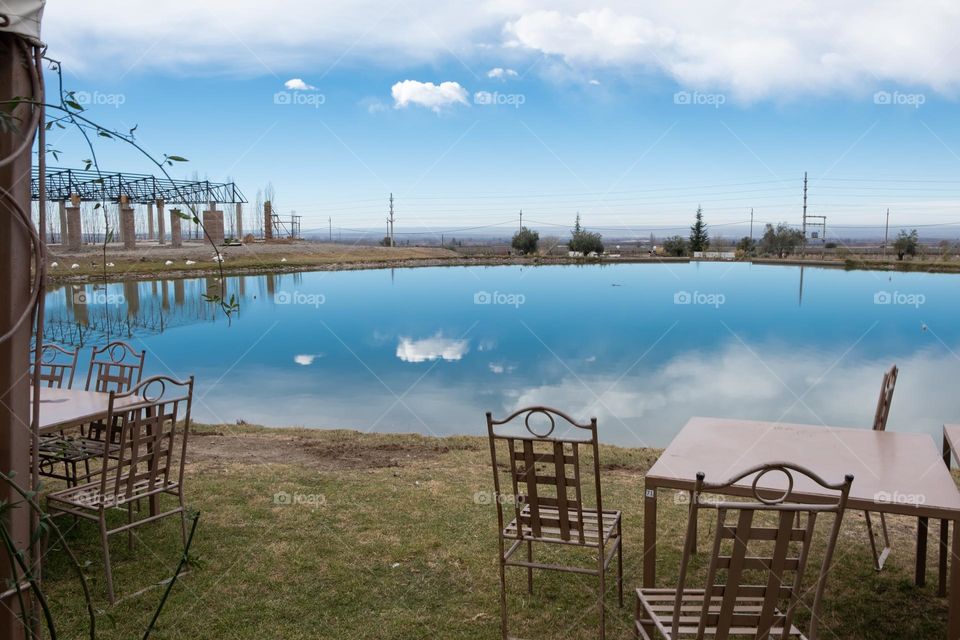 Cafe with metal furniture on the shore of a small blue lake