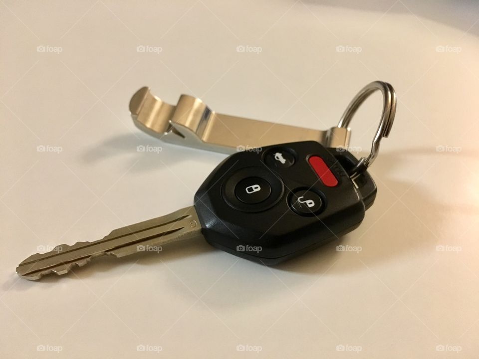 Car keys and bottle cap opener on white table top
