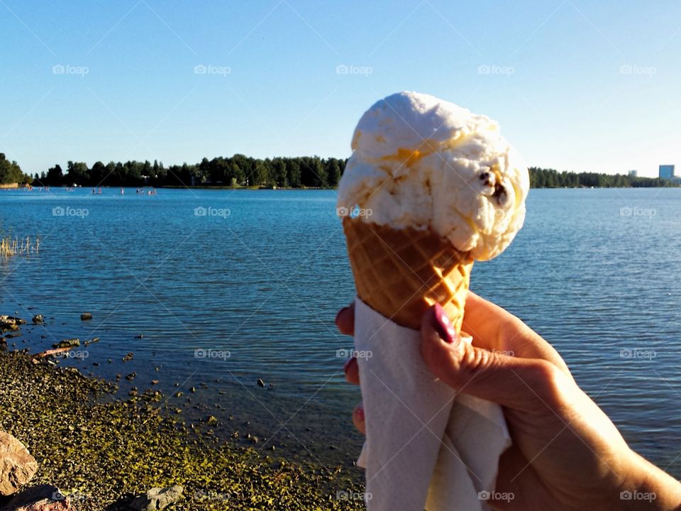 Female hand holding ice cream. Female hand holding delicious ice cream by the Baltic Sea  in Helsinki, Finland  on a sunny August evening.