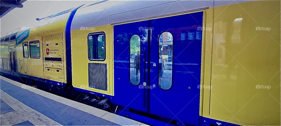 The intensely glowing bright indigo and yellow colors complimentary hues to one another of the train that has just entered the station is accentuating the subject matter immensely. 2022. Hypnotic Productions