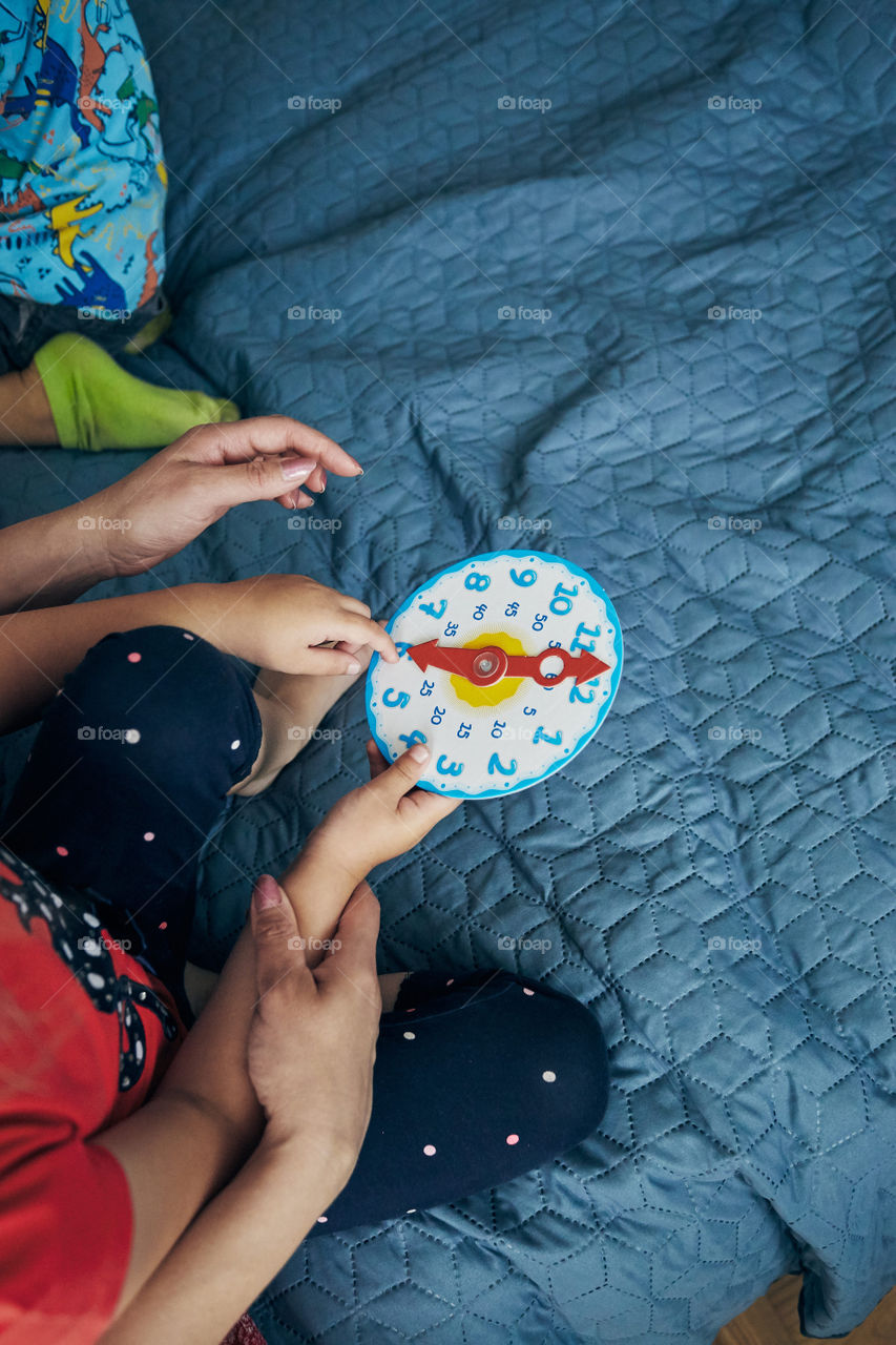 Kids learning how to tell time from clock and set the hands in the correct position. Teaching preschoolers tell time. Candid people, real moments, authentic situations