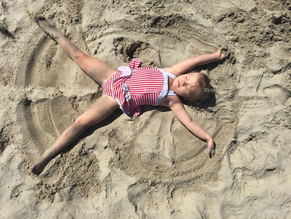 High angle view of a little girl lying on sand