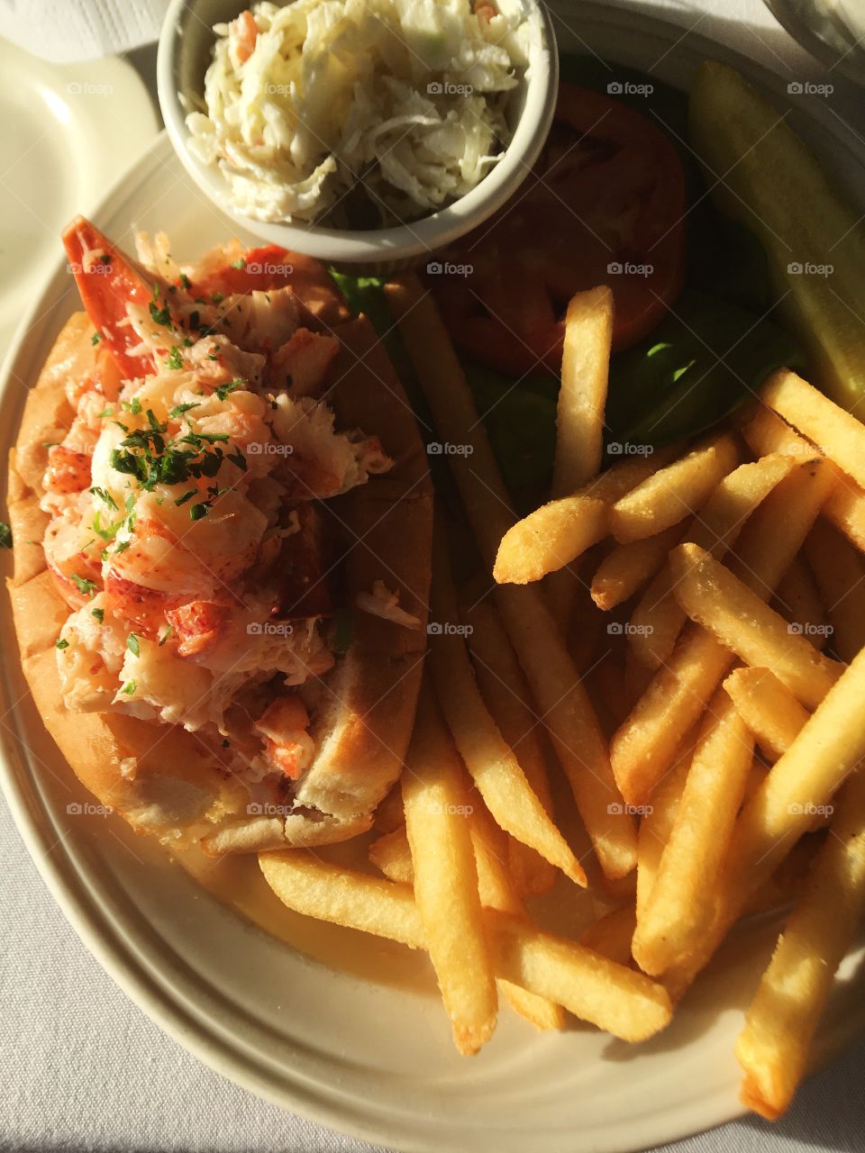 A classic New England lobster roll complete with French fries and coleslaw 