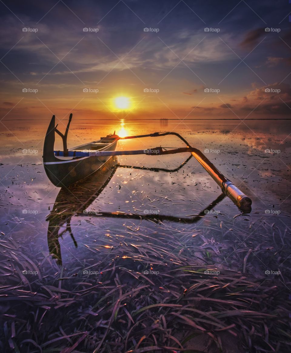 Wooden canoe and sunrise at sanur beach bali indonesia