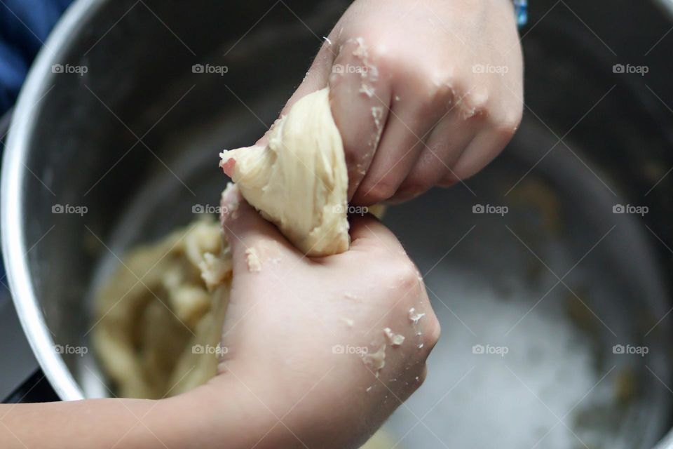 Child's hands are mixing bread dough