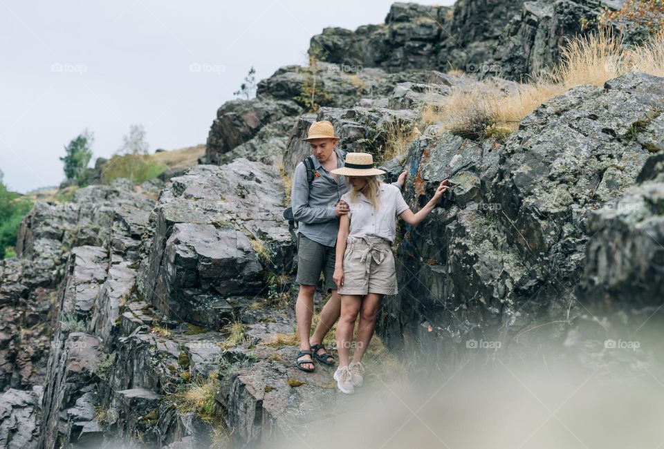 Happy young couple travelers in casual outfits on mountain background. Local tourism, weekend trip