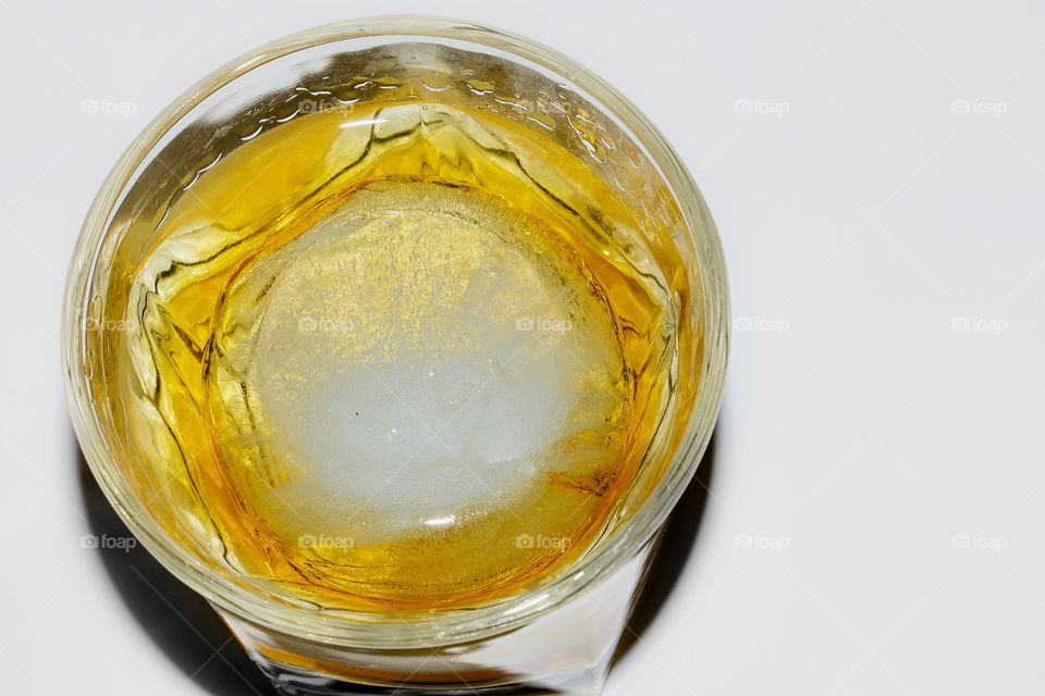 A glass of whiskey with a large round ice ball