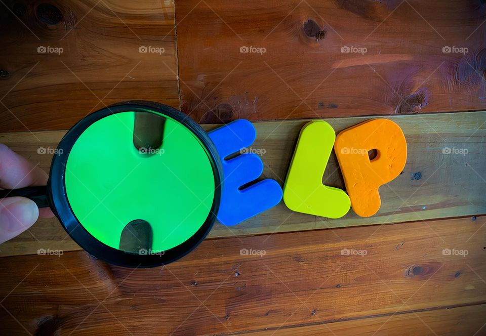 HELP Word Written On Wooden Wall With The Foam Letter H Magnified, Colorful Kids Letters