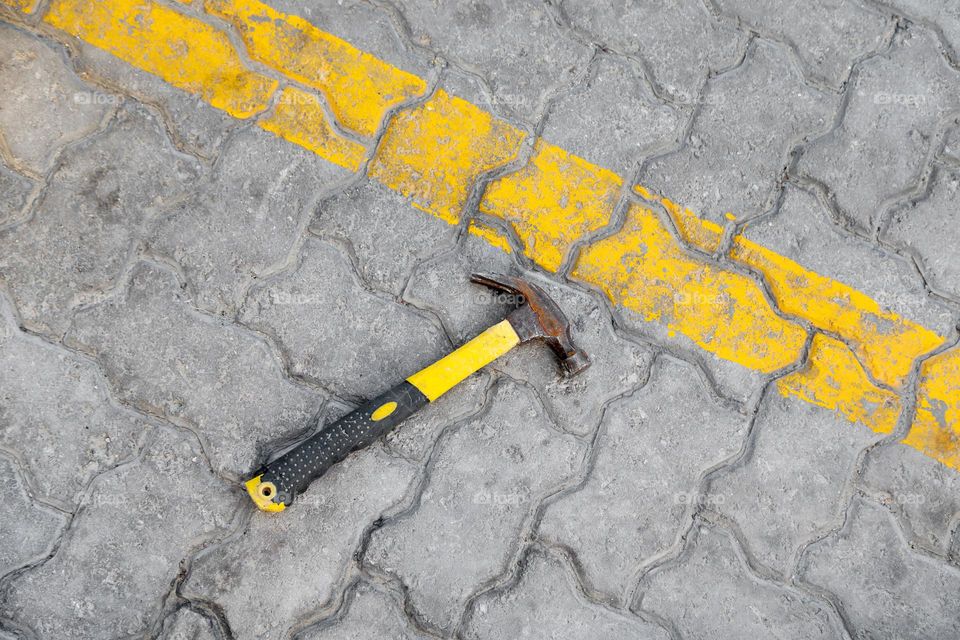 Hammer on an tiled gray asphalt, top view