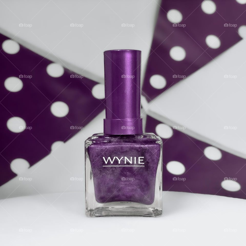 Purple nail polish against a background of purple & white polka dot bunting
