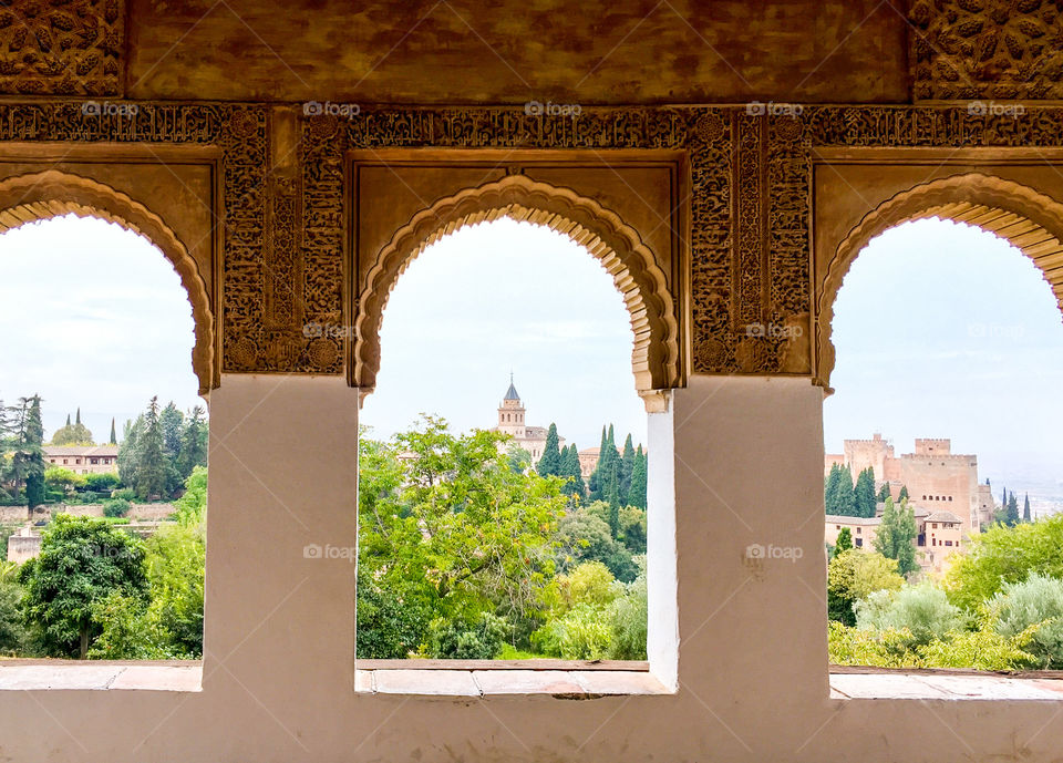 Looking through an ornate moorish arch window at the Alhambra in Spain