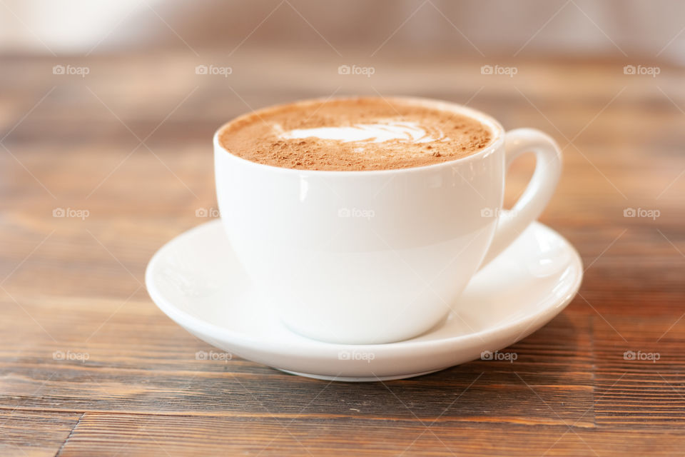 White mug with coffee on wooden table