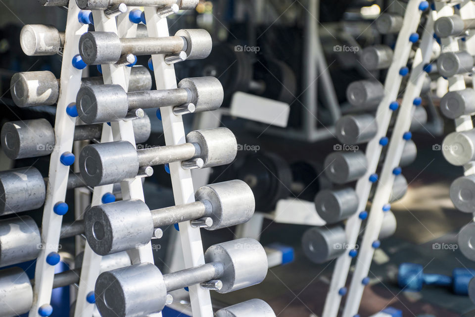 Rows of dumbbells in the gym. Dumbbell set. Close up many metal dumbbells on rack in sport fitness center