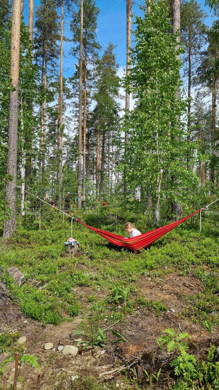 A child in a hammock reading a book in the summer