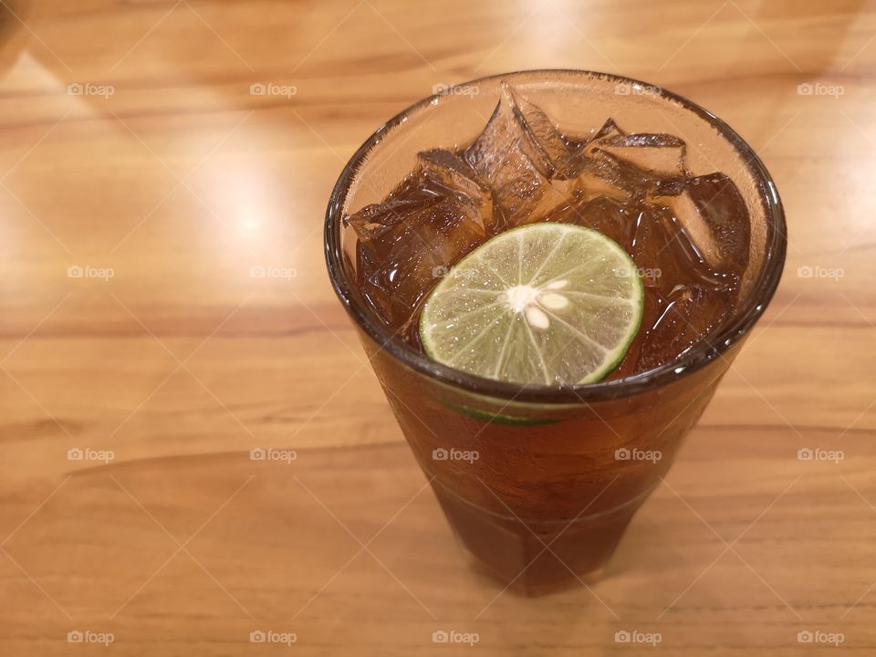 Close-up of ice lemon tea with the wooden table.
