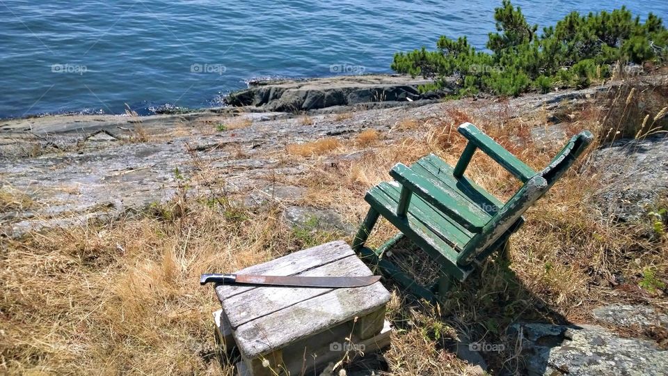 abandoned chair with machete looking out over water
