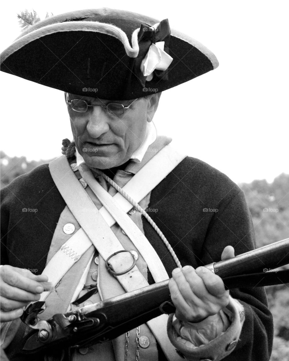 Man reloading his musket in a revolutionary war reenactment 