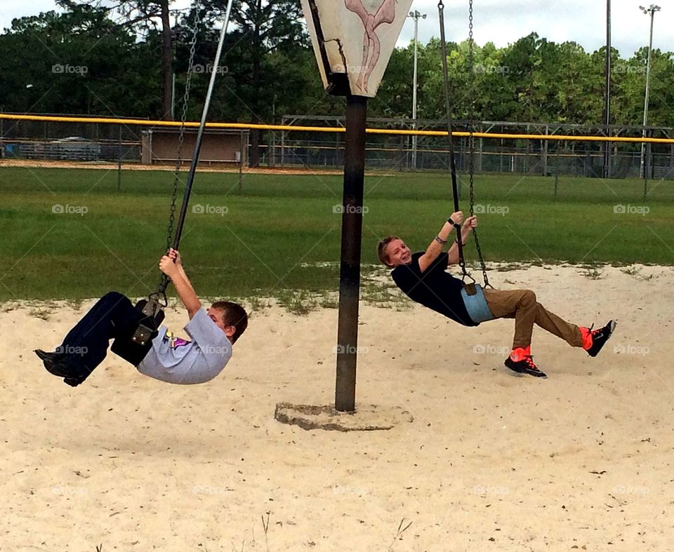 Two boys playing on swing