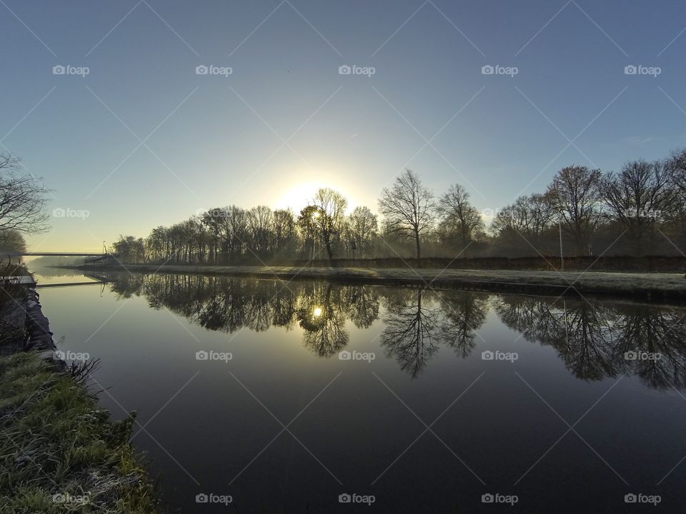 Countryside sunrise showing the colorful sky reflected in the water of the river 