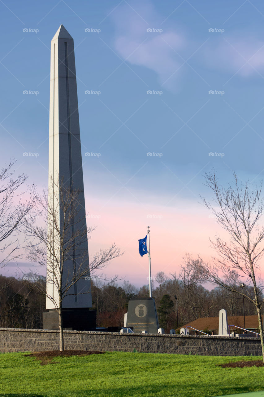 Military monument with contrasts of green grass and pink and blue sky in back ground.