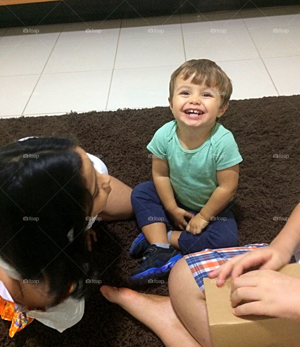 Boy playing with his cousins sitting on the rug.