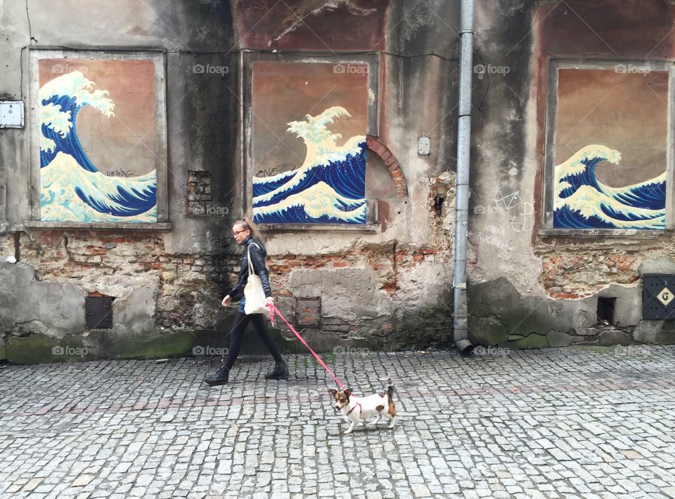 Teenage girl walking on pavement with dog