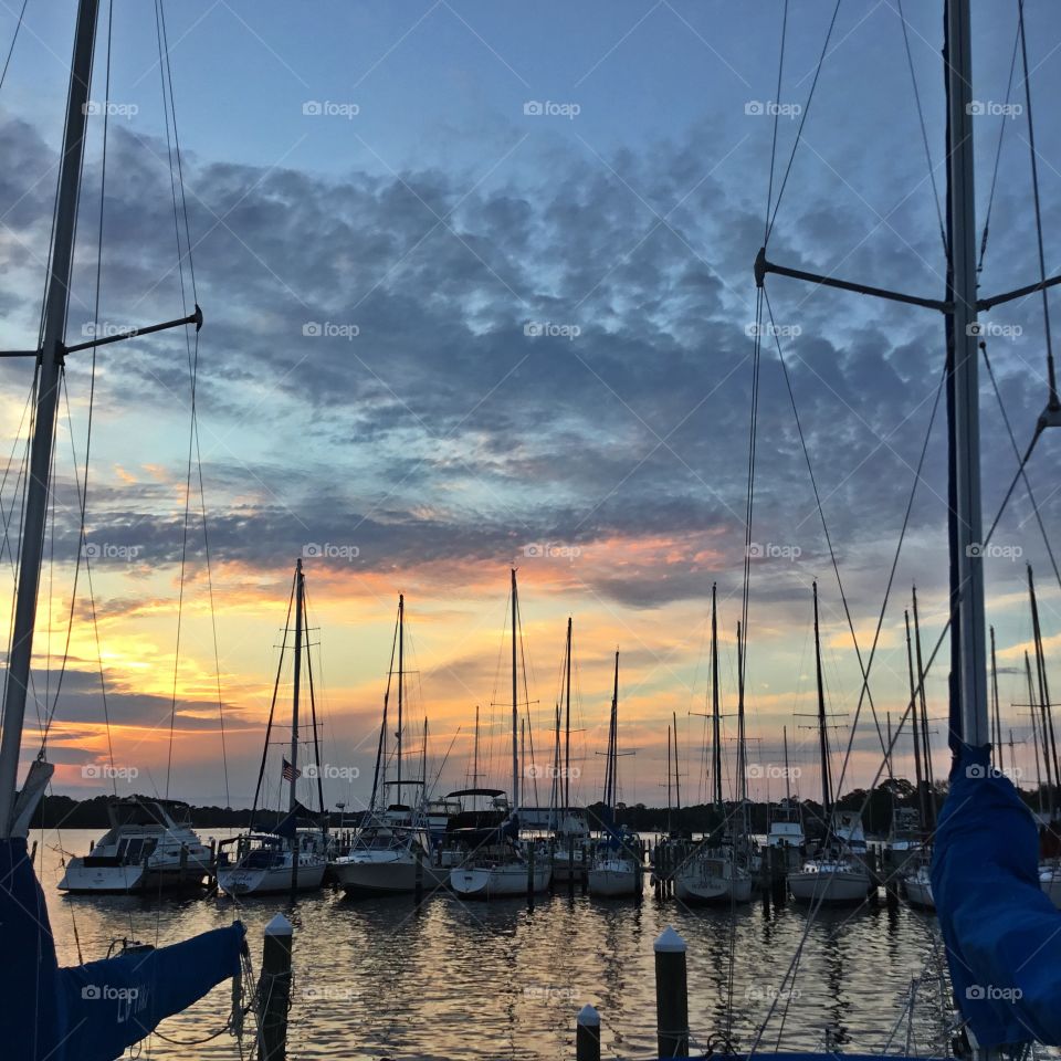 Sailboats moored at the marina with their tall mast silhouette in the spectacular sunset