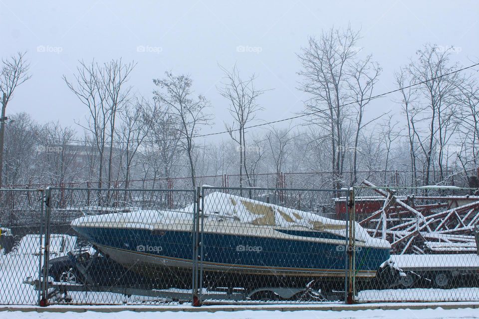 A large speedboat rests until summer in a winter idyll covered with snow