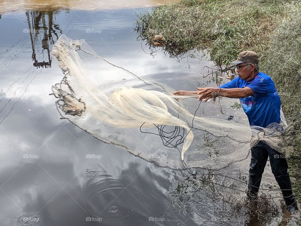 the fisherman throwing net at sungai siak
