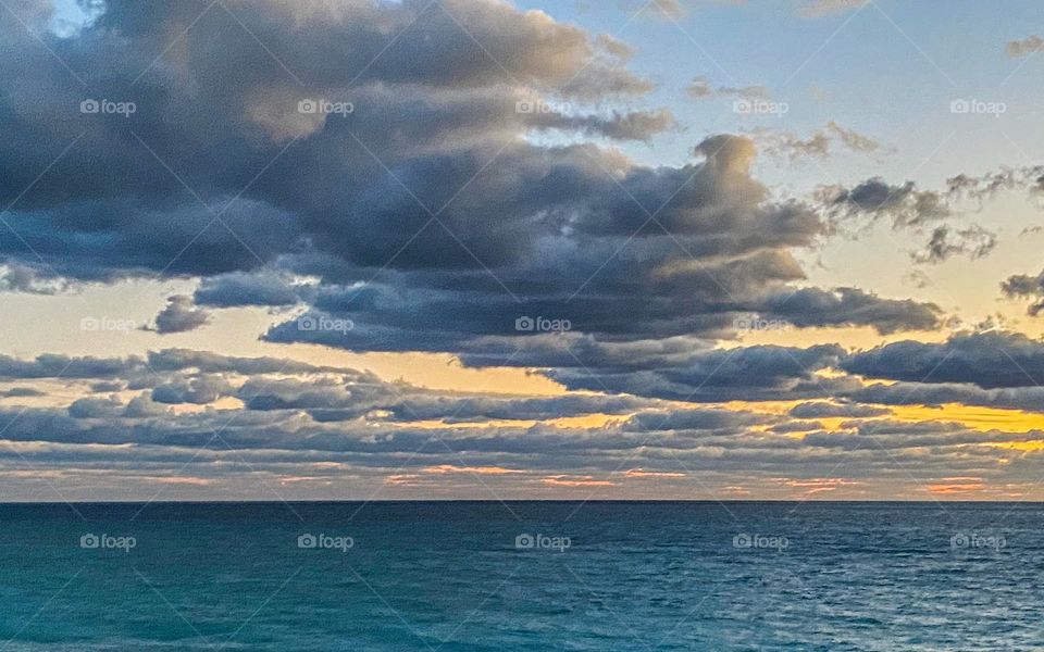 Clouds mission - sunrise over the ocean along the Florida coast. Turquoise water with big clouds overhead and the sun just peeking through.