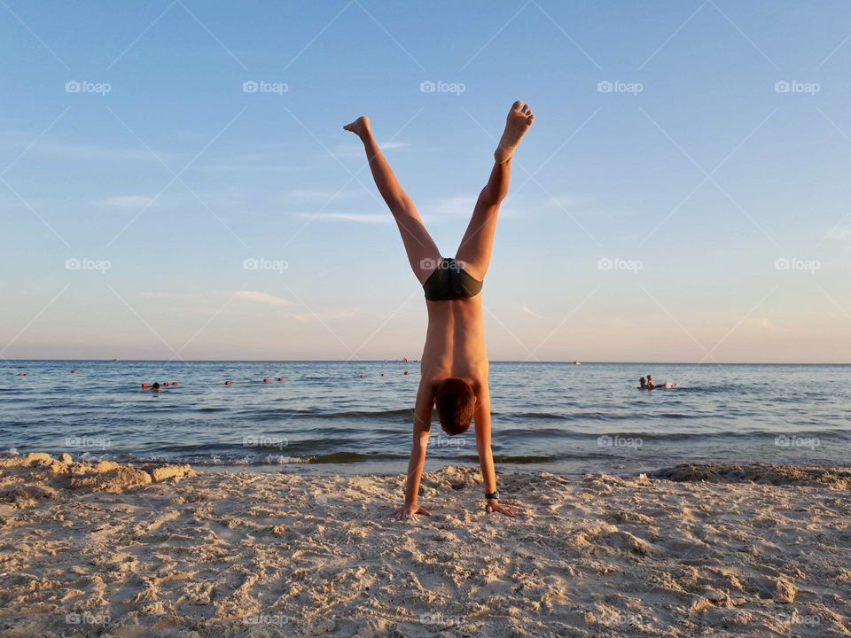Boy does hands stand on the beach 