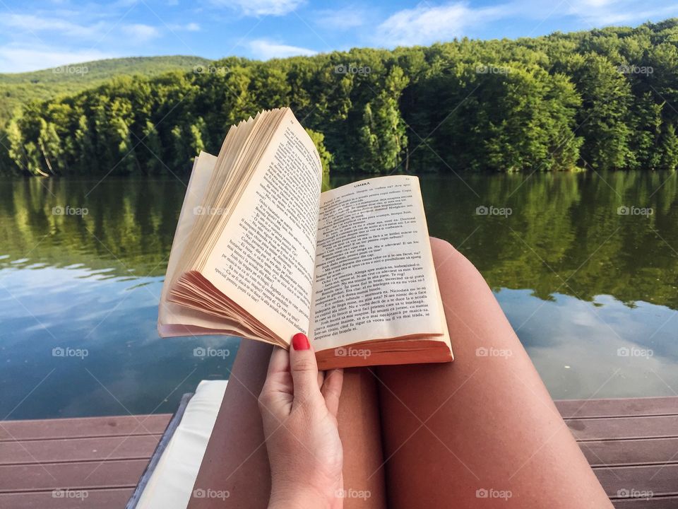 Woman reading by the lake in summer