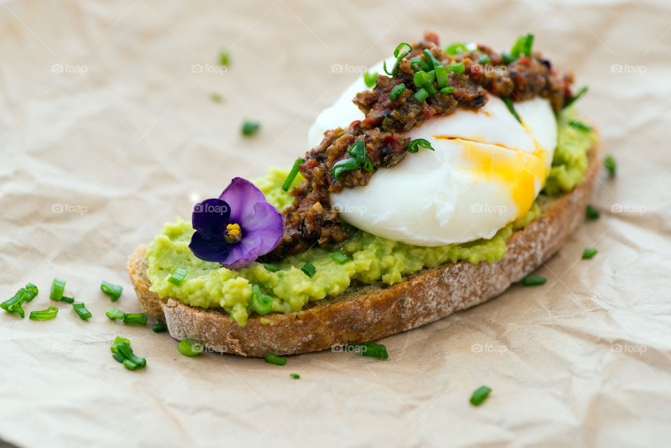 Delicious open sandwich made of avocado, tapenade, pouch-egg on chiabatta