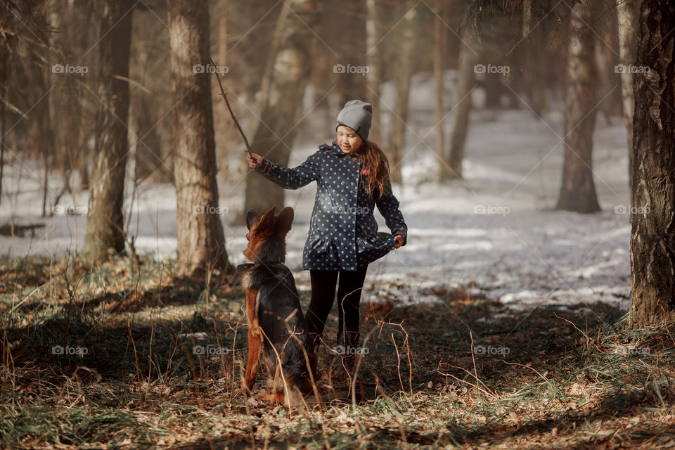 Girl walking with German shepherd puppy in a spring forest 