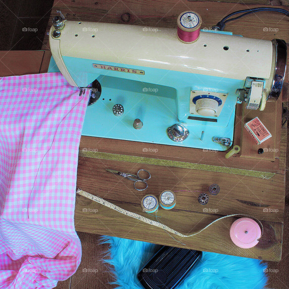 Flat lay featuring a vinntage Harris sewing machine in powder blue, ready to stitch pink and white check fabric, with assorted accessories 