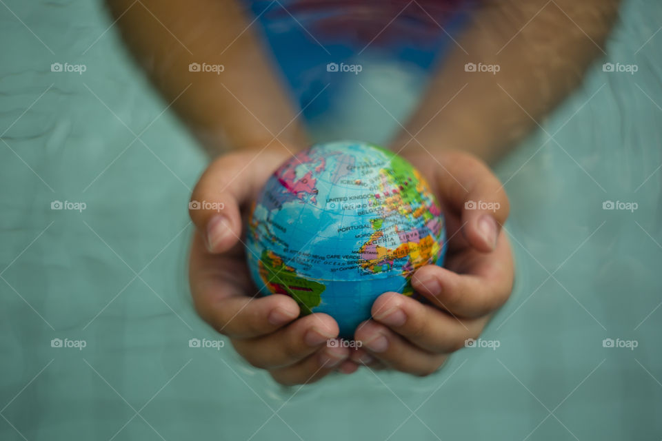 overhead looking down on hands holding world sphere, ocean Atlantic 4 continents Europe, Africa, north and south America