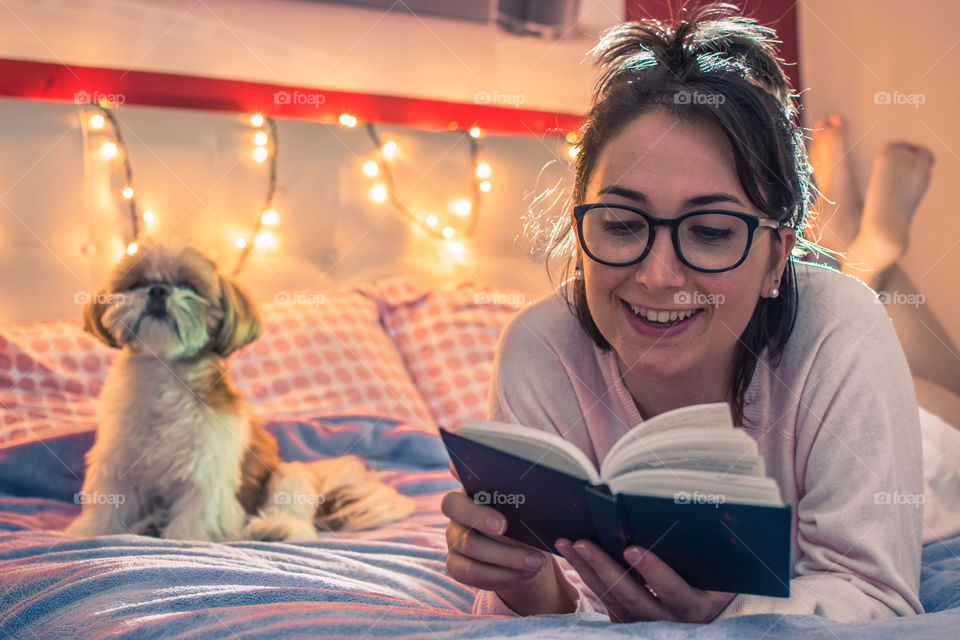 Cute girl reading in bed with her dog