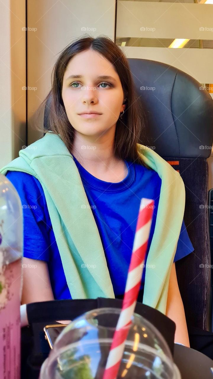 a girl on a train in bright clothes looks thoughtfully out the window