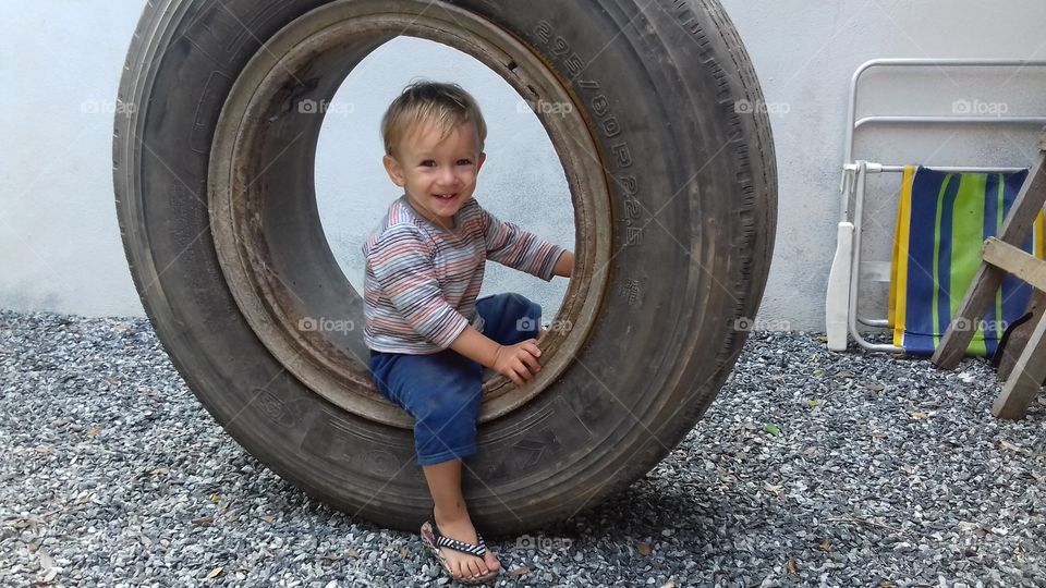 Happy boy sitting on tire