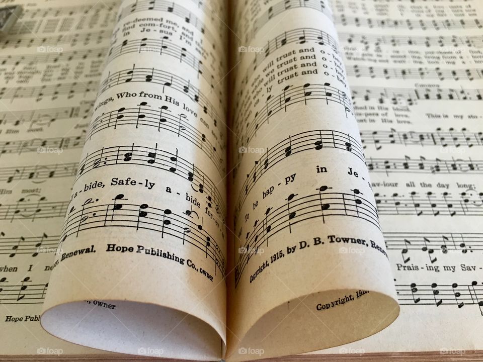 Old antique Christian church hymnal book opened with pages artistically into heart or scroll shape. Abide with me