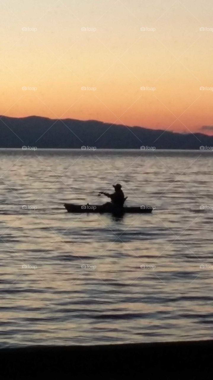 Tranquil fisherman closeup silhouetted against gorgeous sunset on Flathead Lake Montana